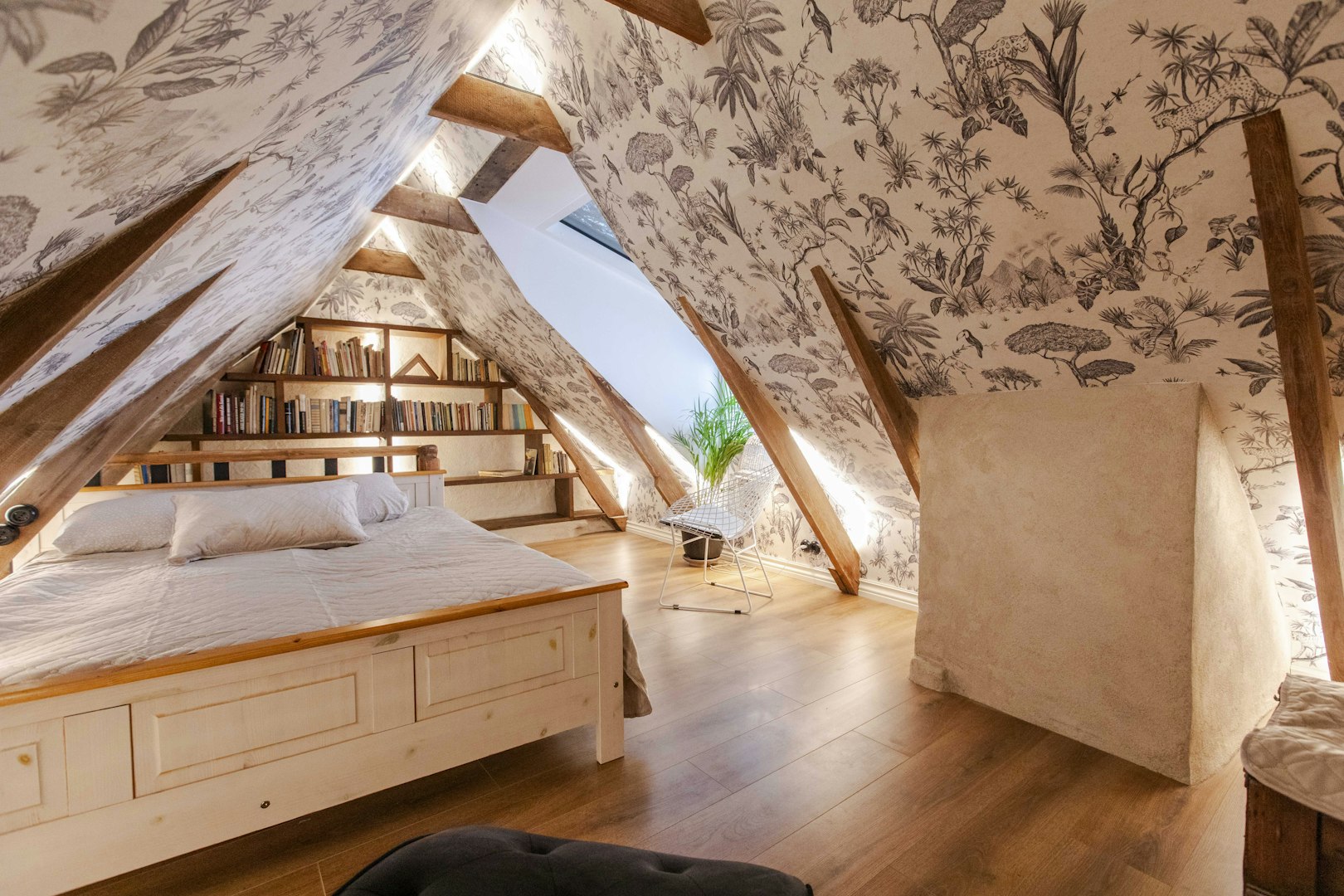 Tapetserat loftsovrum med snedtak, synliga takbjälkar och naturmönstrad fondtapet – inspiration för personlig inredning och renovering